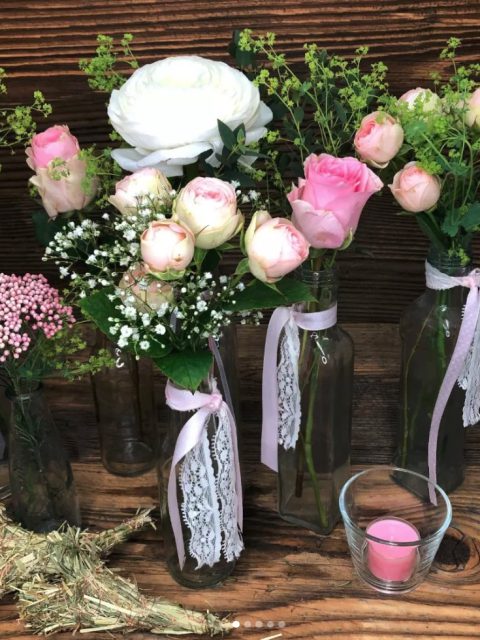 verschiedene kleine vornehmlich in Rosa- und Weißtönen Blumensträuße in Glasflaschen